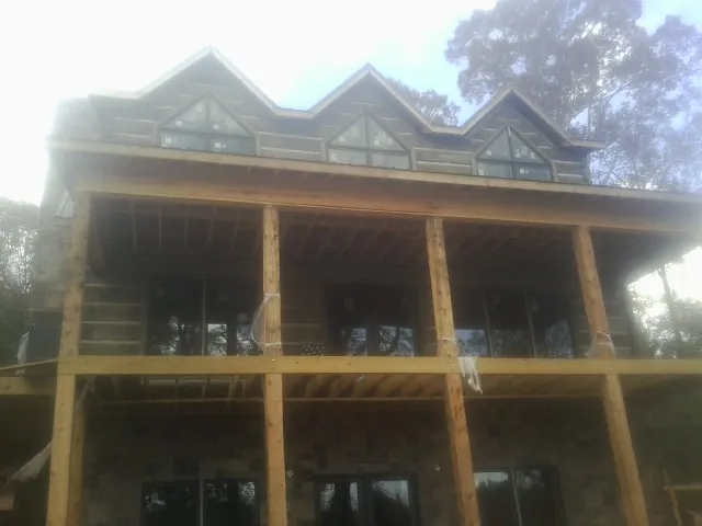 Dormers and porch framing on a large log home under construction — Roof Coating work by our crew in Springport