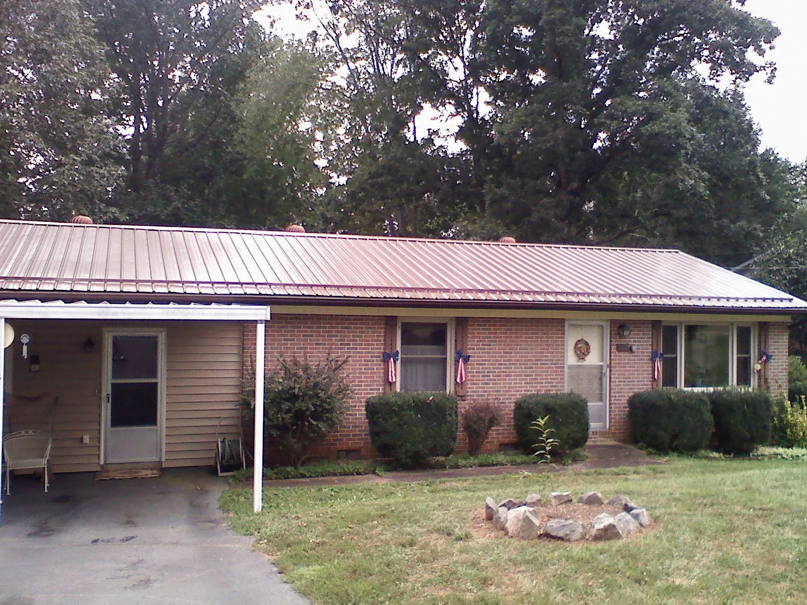 Bronze metal roof and carport on a brick ranch home — Roof Repair work by our crew in Springport