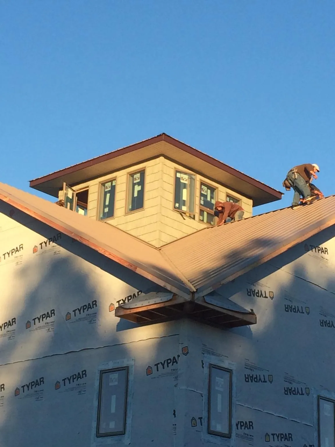 Roofers working around a rooftop cupola on a new metal roof at sunset — Roof Waterproofing in Springport by Roofing Brothers
